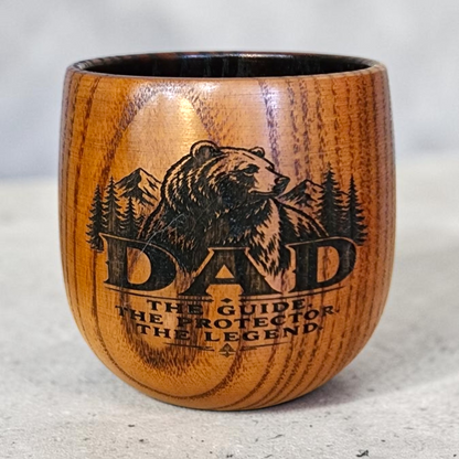 Wooden cup with engraved text on a brown surface